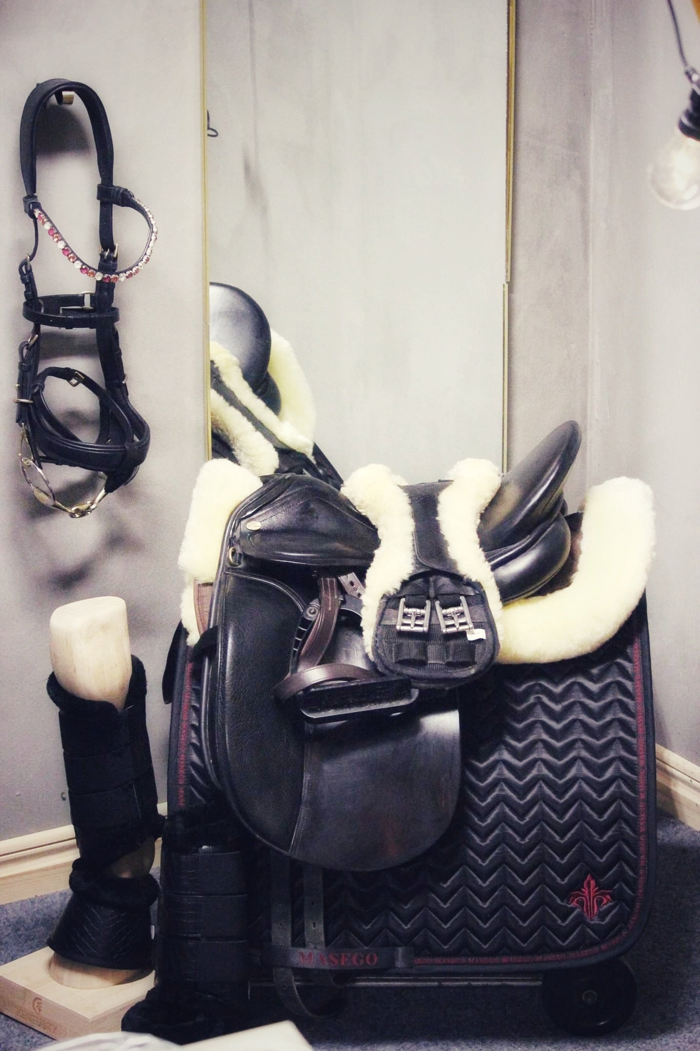 Black fishbone quilted dressage saddle pad with cherry embroidery and satin finish, designed for steady fit and easy cleaning.