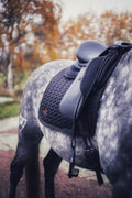 Black dressage saddle pad with fishbone quilting and golden brown embroidered logo on a gray horse
