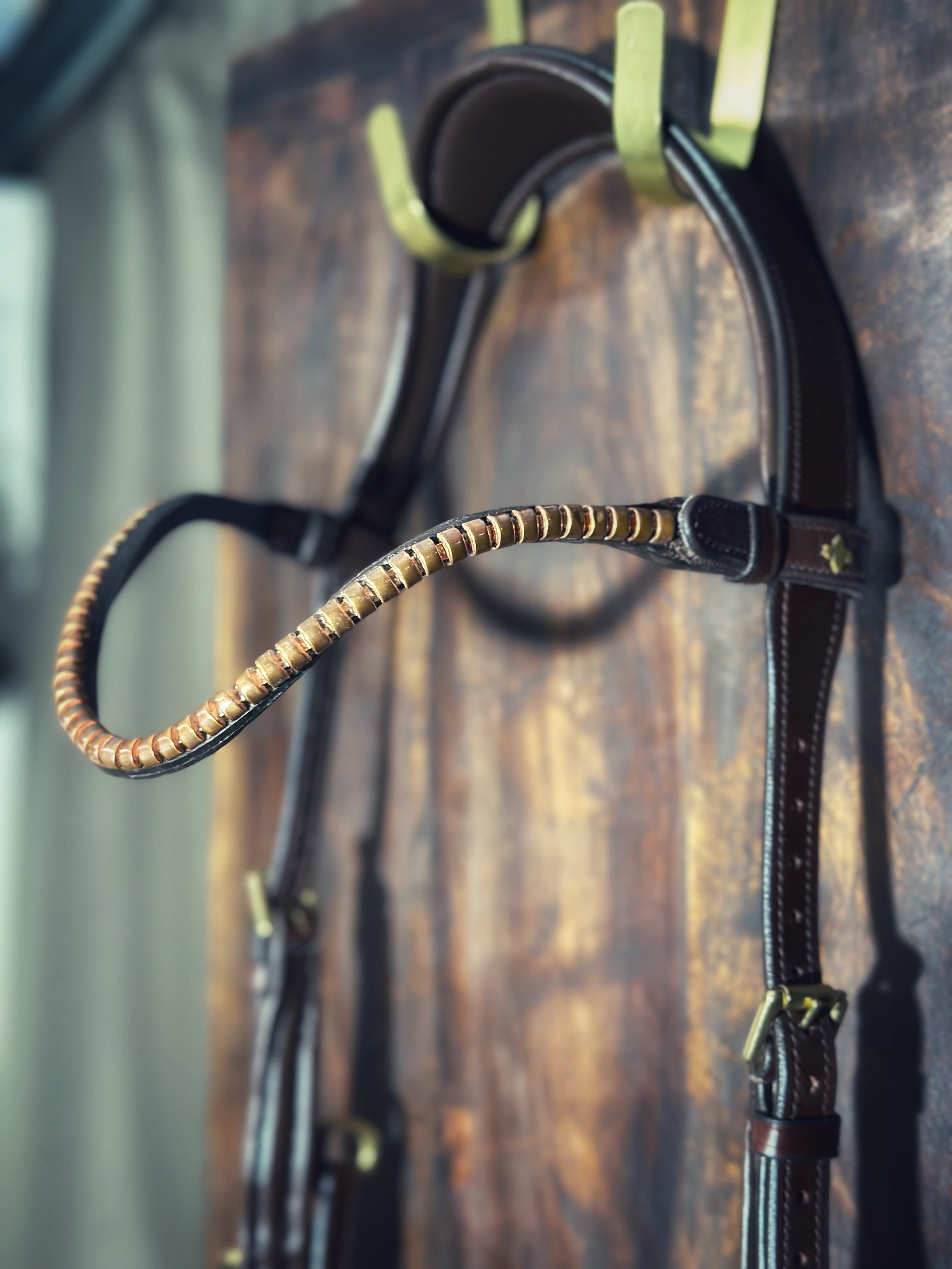 Slim klinker Golden peach Italian leather bridle with brass logo and easy switch feature hanging on wooden wall